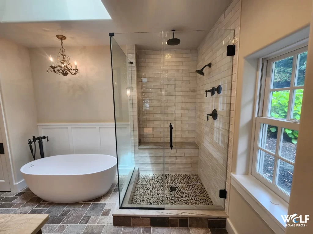 Bathroom remodel in Berwyn, PA with a tiled walk-in shower, freestanding soaking tub, black fixtures and tile flooring.