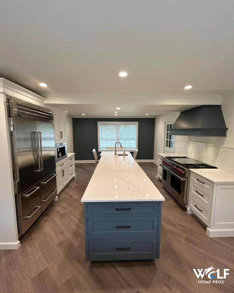 Completed Berwyn, PA kitchen remodel with white shaker cabinetry, blue island, quartz countertops, custom range hood and stainless steel appliances.