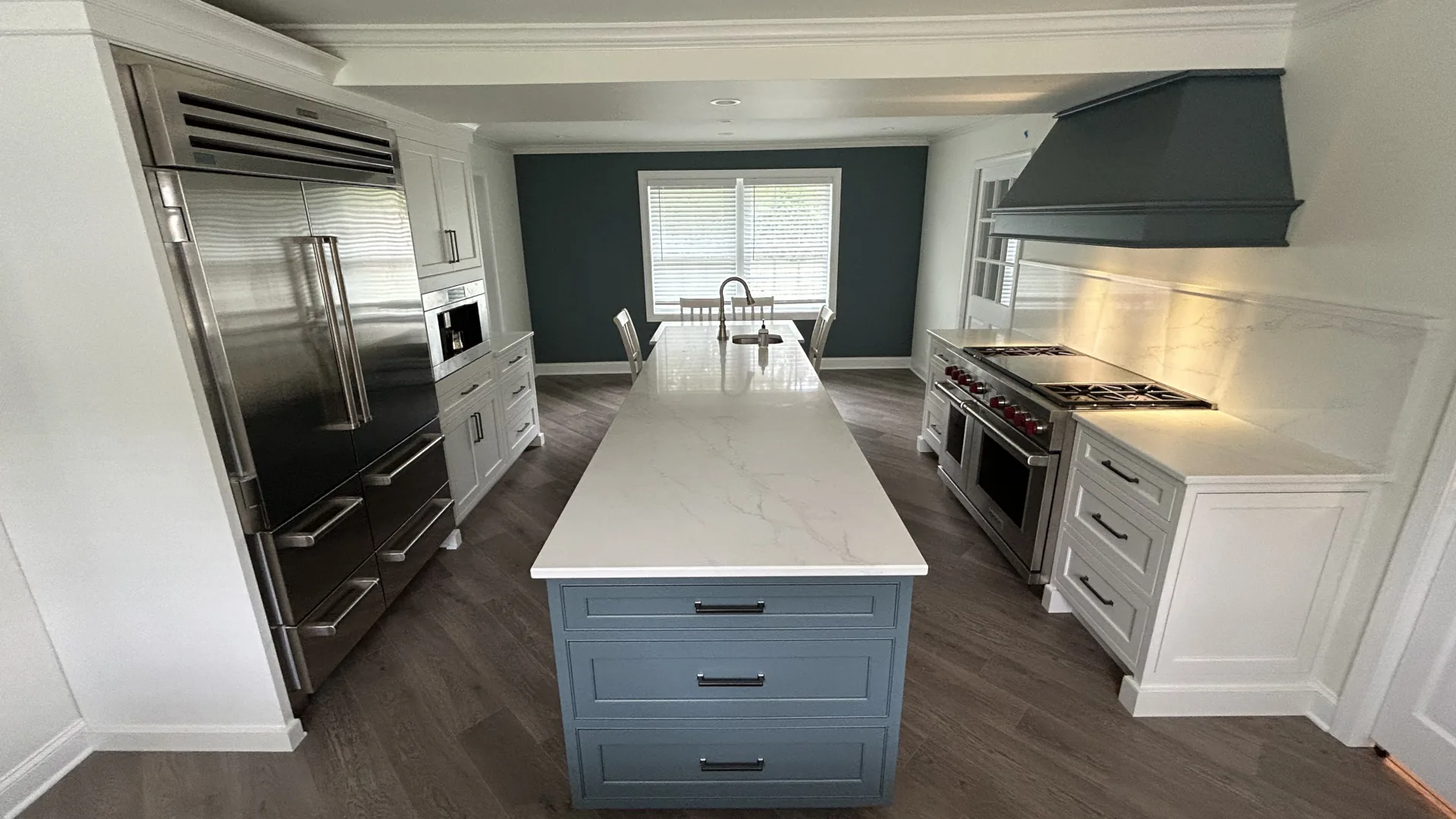 Kitchen remodel in Berwyn, PA with custom cabinets, a large island, new appliances, hardwood floors, and a custom range hood by Wolf Home Pros