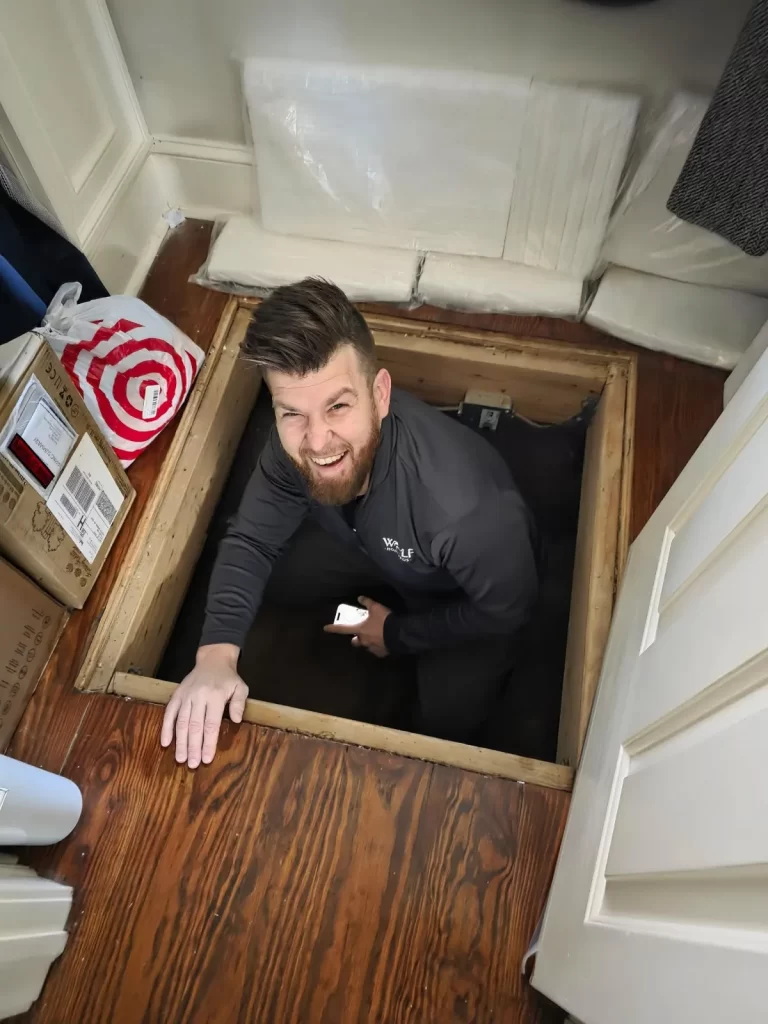 Dan Wolf smiling up from a floor opening during a Wolf Home Pros project.