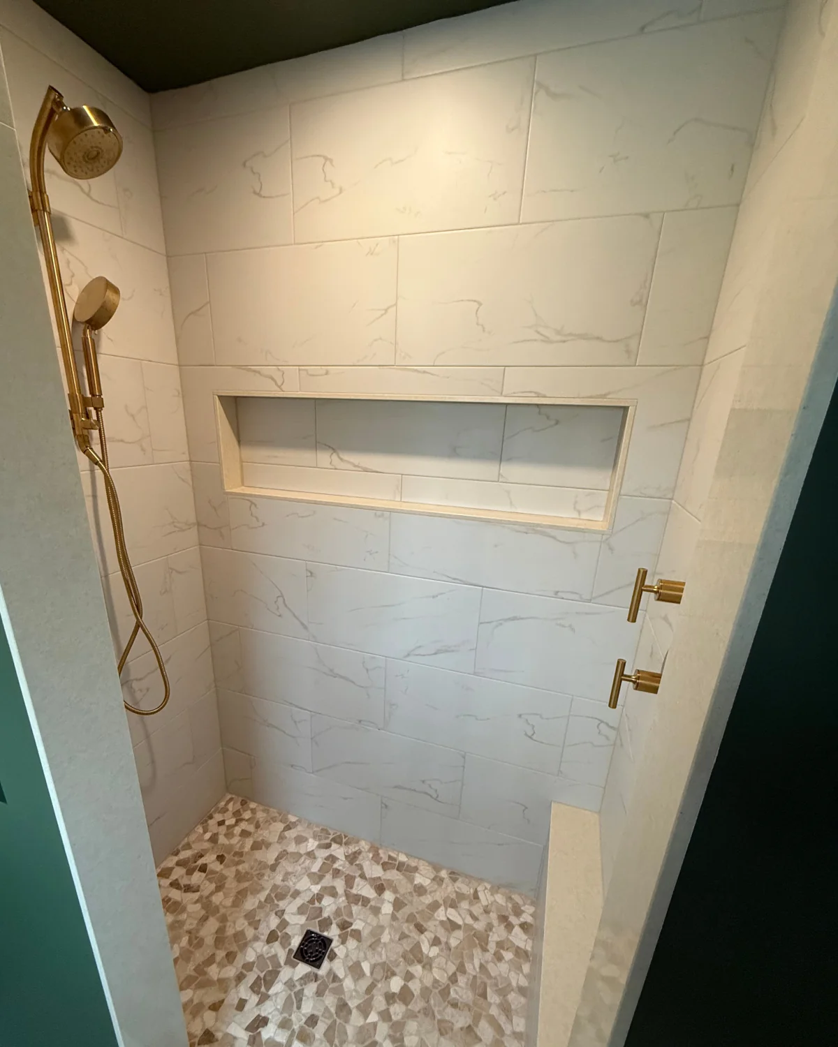 Finished walk-in shower in Downingtown, PA with marble-look wall tile, recessed niche, mosaic shower floor and updated fixtures.