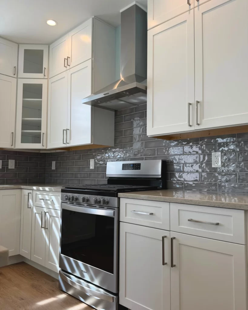 Close-up of a Downingtown, PA kitchen remodel with custom white cabinetry, stainless steel range and hood, gray tile backsplash and new countertops.