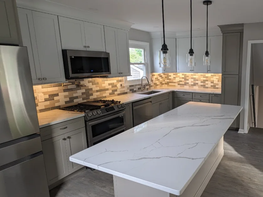 Finished kitchen remodel in Phoenixville, PA with a large island, custom cabinetry, tile backsplash, new appliances and pendant lighting.