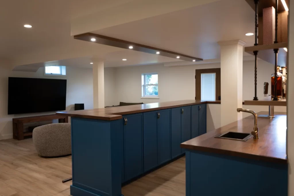 Close-up view of a custom wet bar by Wolf Home Pros in West Chester, PA featuring blue cabinetry, wood countertops, sink area, and custom shelving.