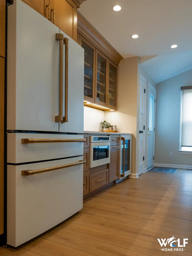 Completed kitchen remodel by Wolf Home Pros in Chester Springs, PA with custom cabinetry, paneled refrigerator, built-in oven, beverage refrigerator, under-cabinet lighting, and finished storage details.