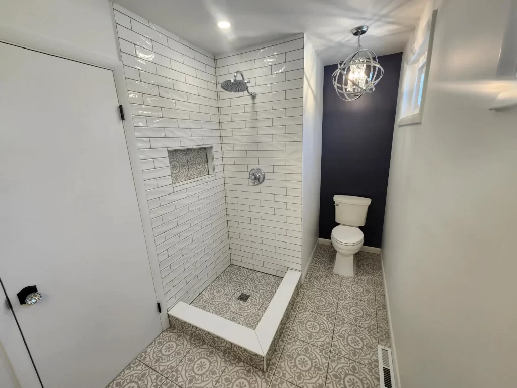 Bathroom remodel in Downingtown, PA with a tiled walk-in shower, patterned tile floor, updated fixtures, and chandelier lighting.