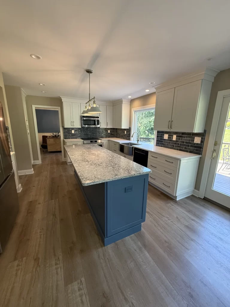 Finished Downingtown, PA kitchen remodel with white cabinetry, blue island, hardwood flooring, new sink, and updated lighting.