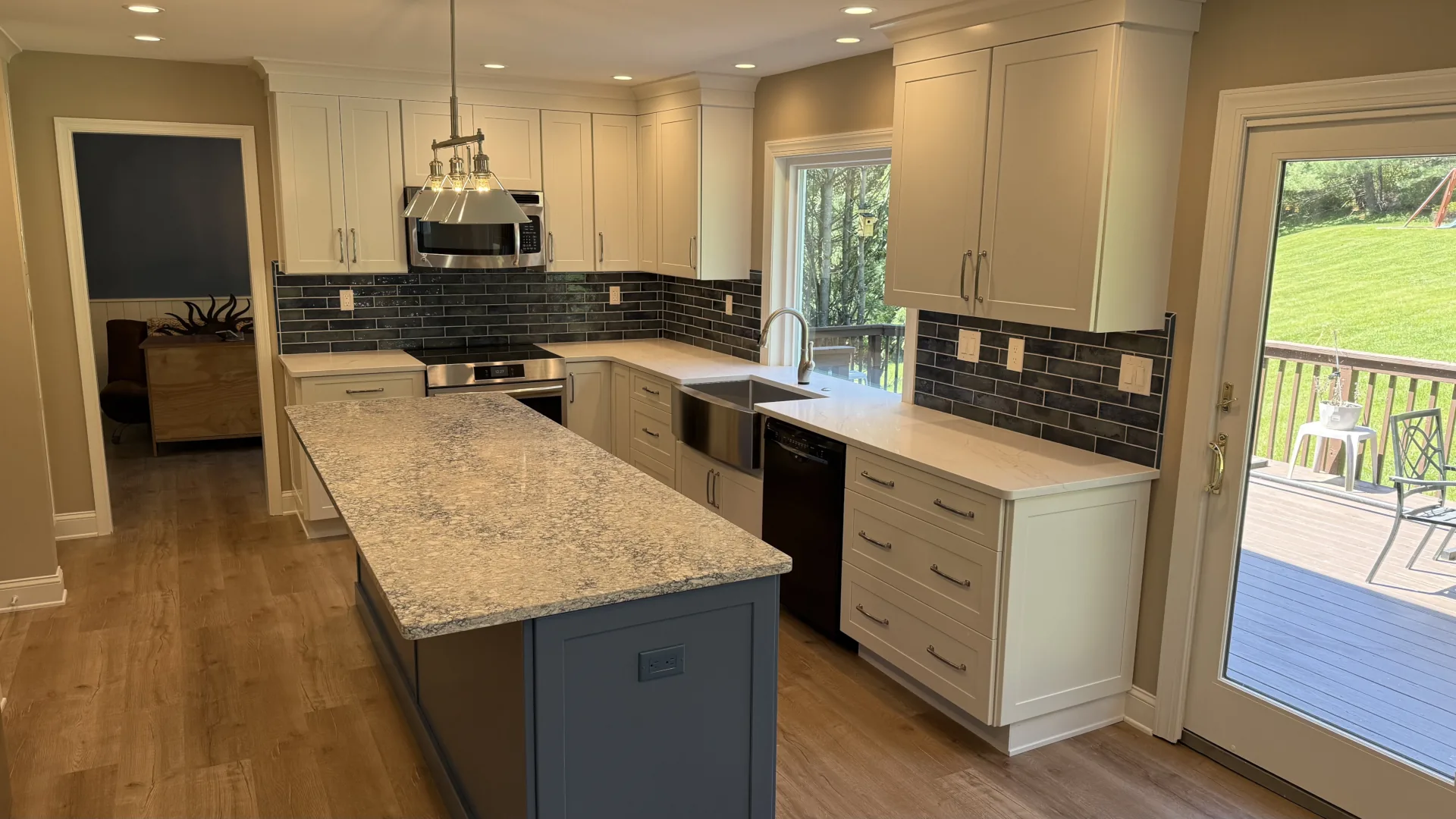 Finished kitchen remodel in Downingtown, PA with new cabinetry, island, hardwood floors, sink, lighting, and access to the back deck.