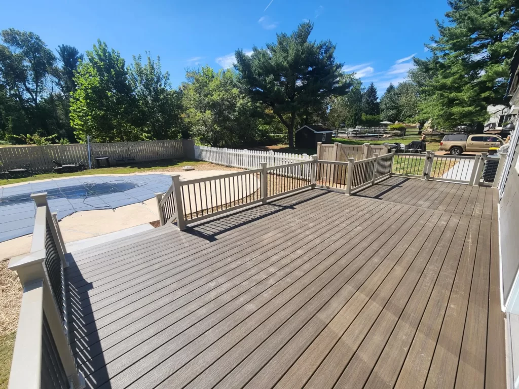 Finished deck build in Phoenixville, PA with new decking, railings, stairs, and access to the backyard pool area by Wolf Home Pros.