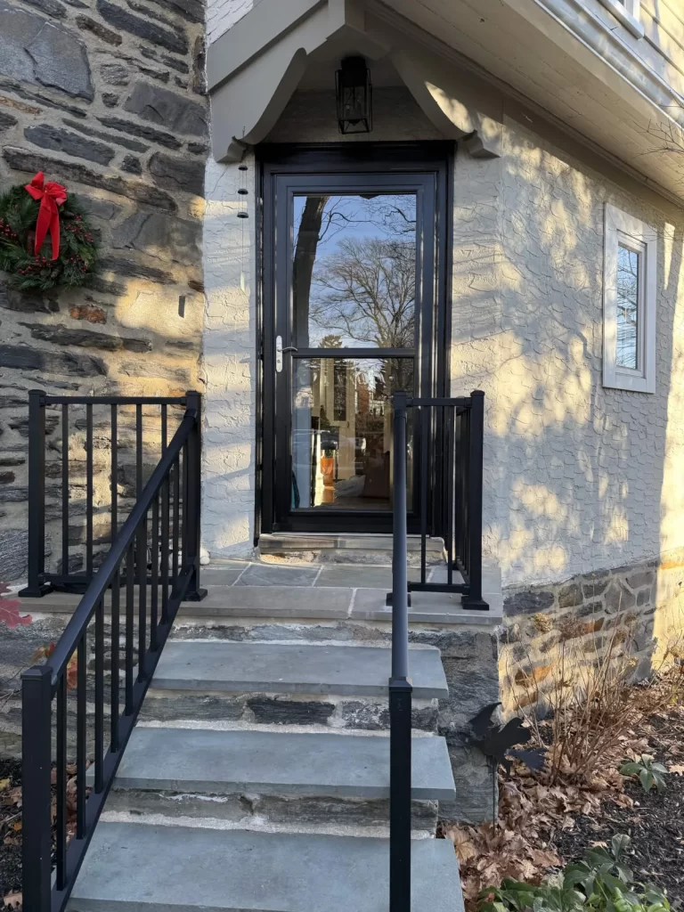Front door replacement in St. Davids, PA with a new black glass entry door and custom carpentry by Wolf Home Pros.