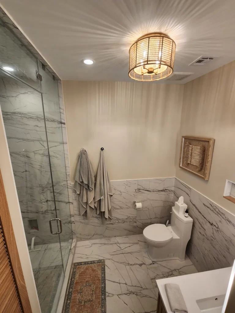 Finished bathroom remodel in Villanova, PA with a tiled walk-in shower, large-format tile flooring and walls, updated fixtures, and new lighting.
