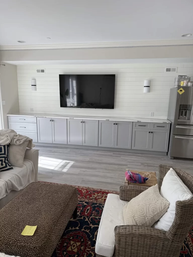 Custom entertainment center in Wayne, PA with built-in cabinetry, countertop, wall-mounted television, and paneled feature wall.