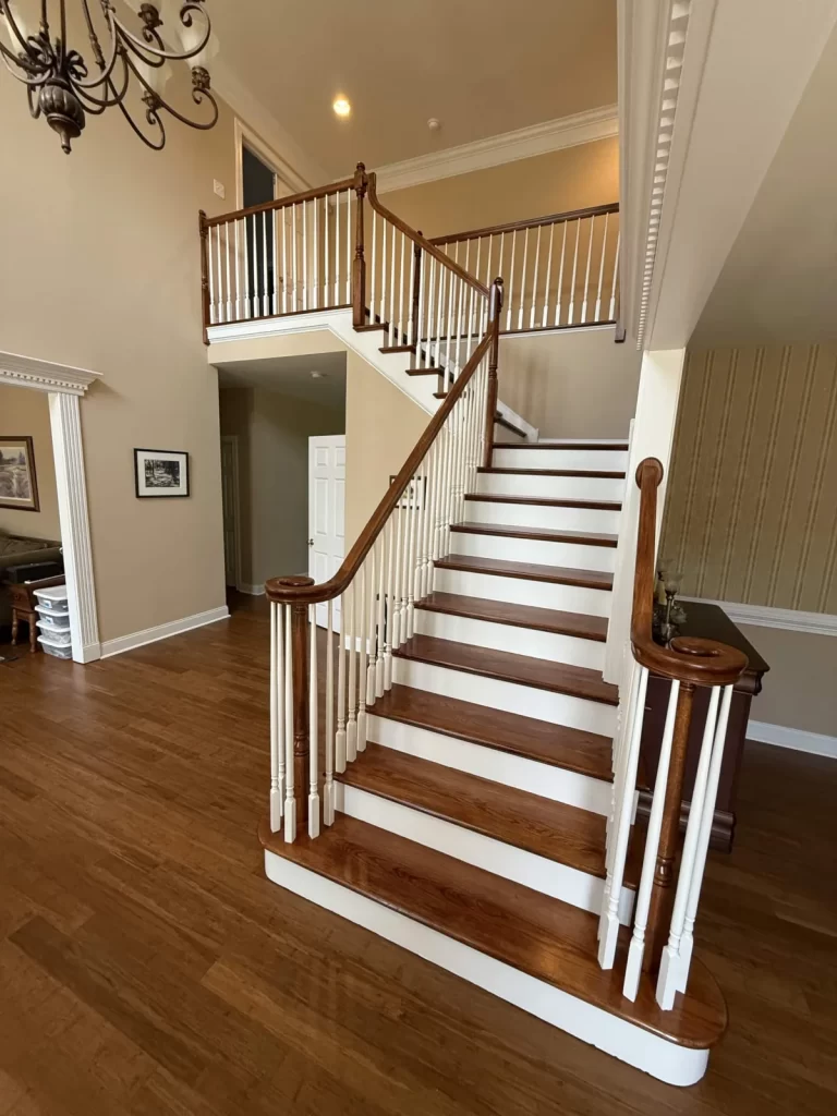 Finished staircase and railing in Wayne, PA with refinished wood treads, handrails, white balusters, and upper-level railing.