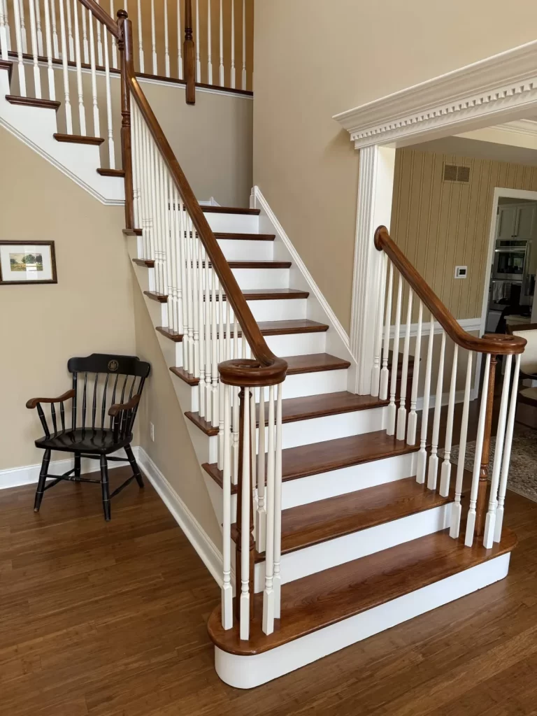 Close view of a refinished staircase in Wayne, PA with wood treads, curved handrails, white balusters, and white risers.