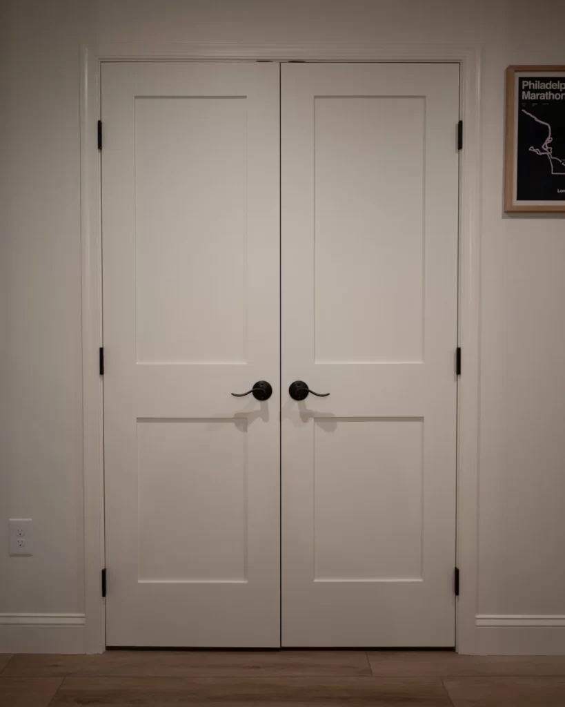 Finished double doors in a West Chester, PA basement remodel with white trim, black hardware, and wood-look flooring.