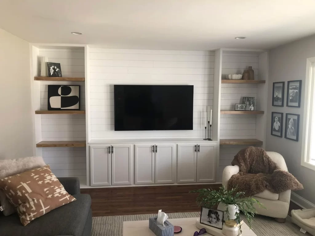 Custom entertainment center in West Chester, PA with built-in cabinetry, floating wood shelves, shiplap, and wall-mounted television.