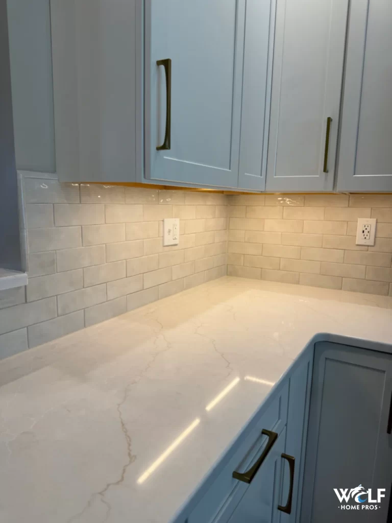 Close-up of a West Chester, PA kitchen with light tile backsplash, white cabinetry, countertop, and under-cabinet lighting.