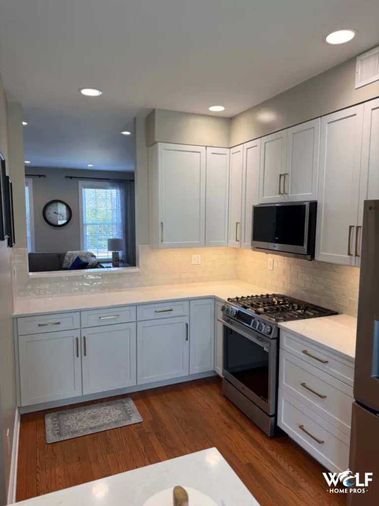 Kitchen project in West Chester, PA with white cabinetry, light tile backsplash, countertops, appliances, and hardwood flooring.